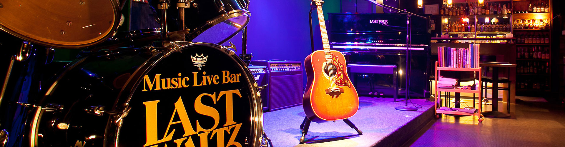 ドラムセットとギターの置かれた店内ステージの写真